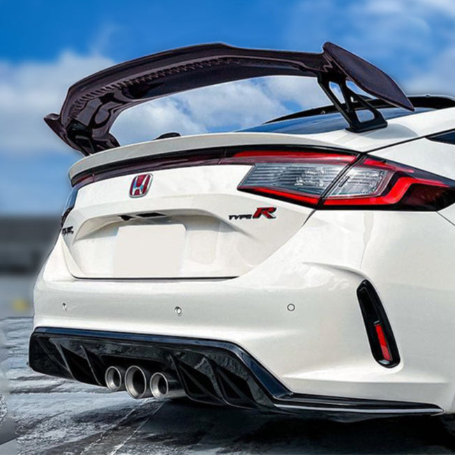 Carbon fiber car spoiler on a white background with a car featuring the spoiler in the background.